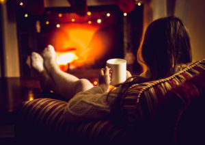 Woman relaxing by a fire with a warm beverage